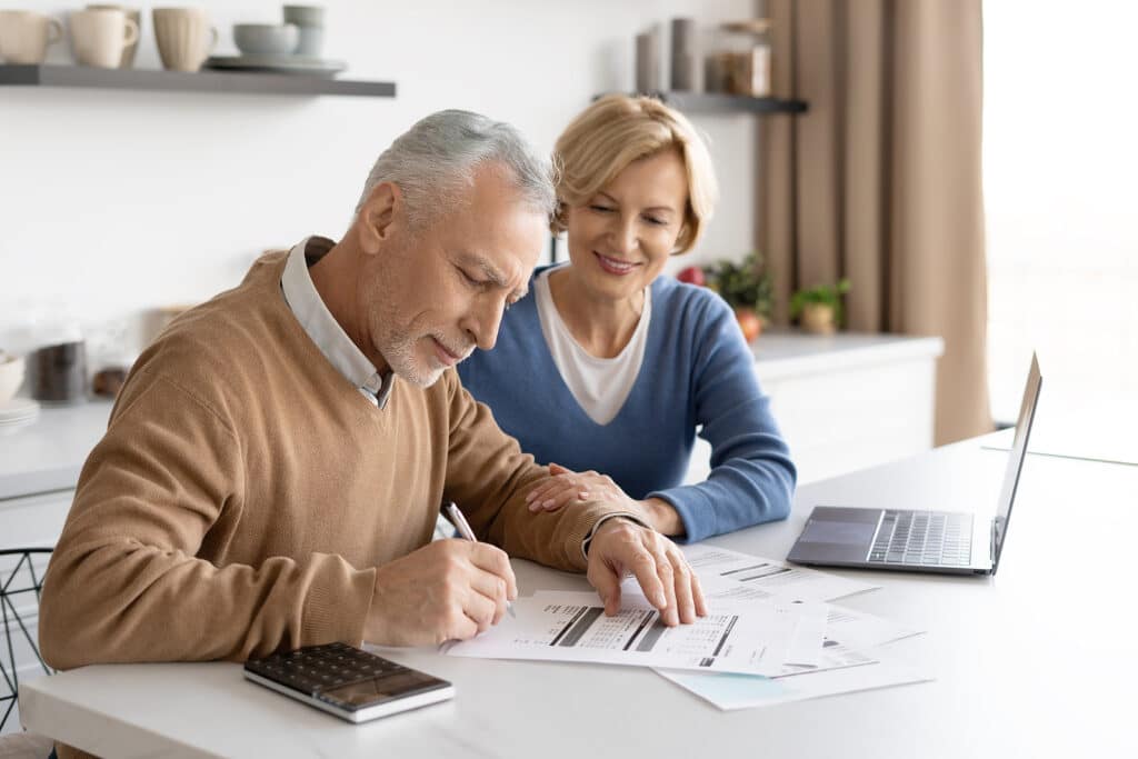 Side View Of Happy Senior Couple Counting Taxes Together In Cozy